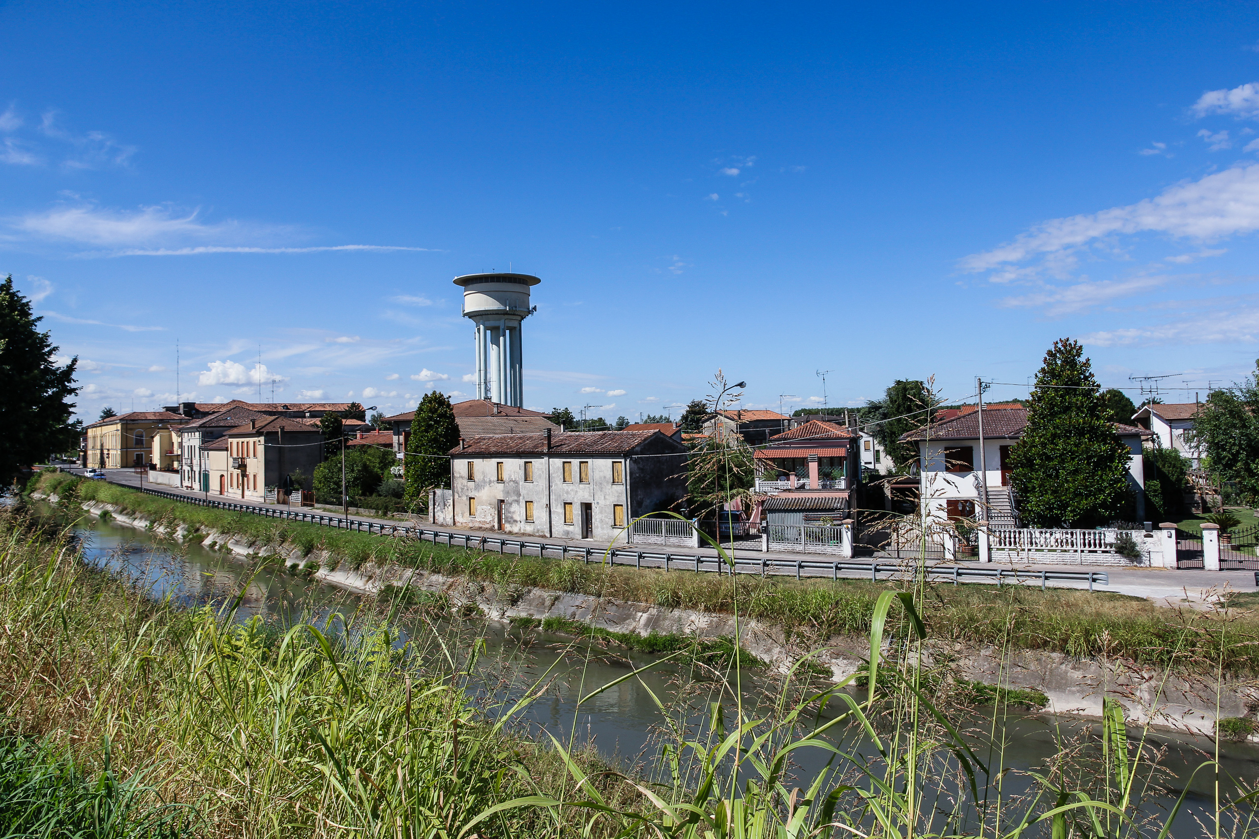 Wasserturm über den Dächern, davor der Kanal mit niedrigem Pegel